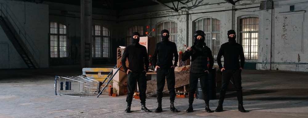 Four masked burglars standing in a warehouse