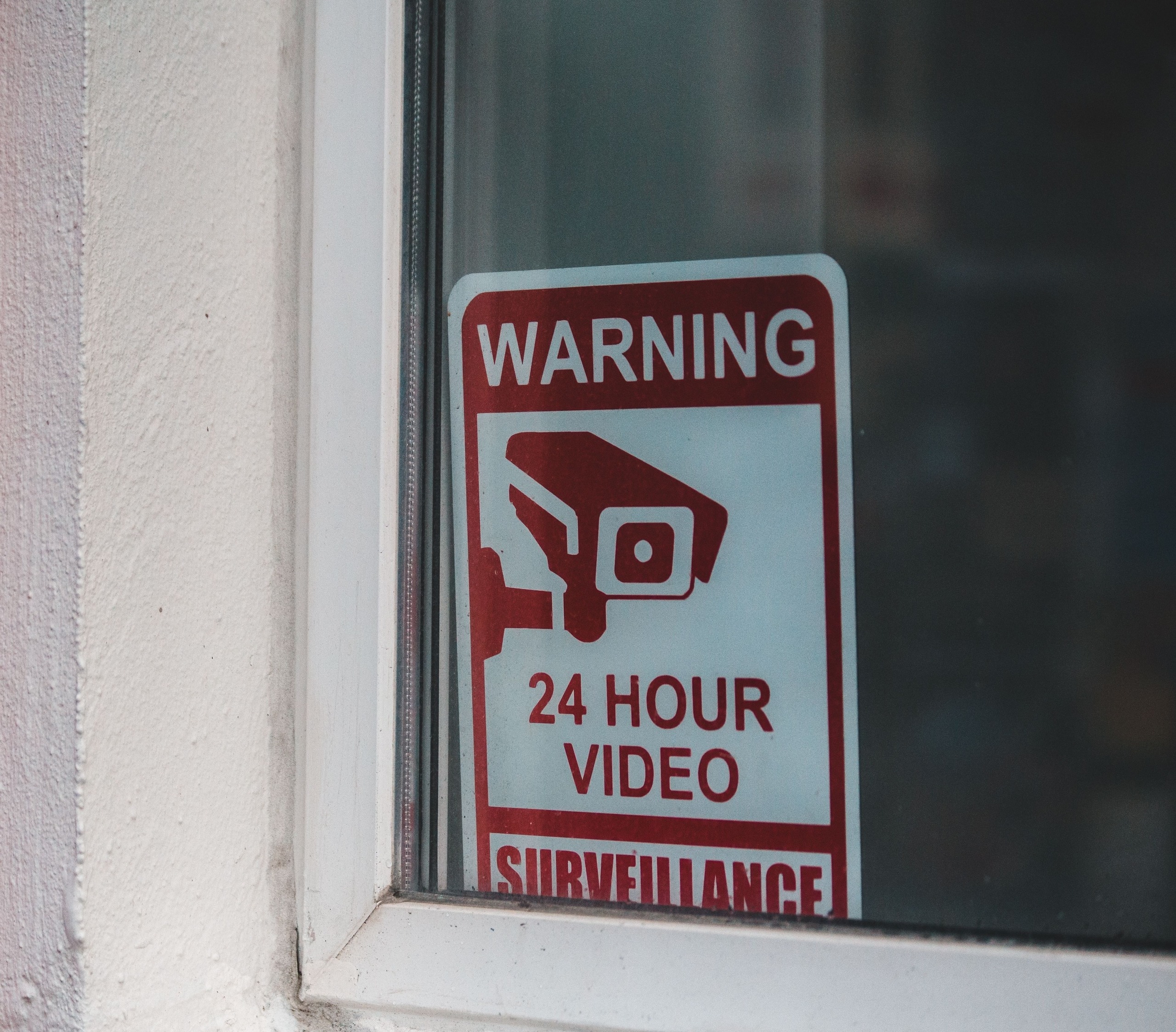 24 hour video surveillance warning sign in a window
