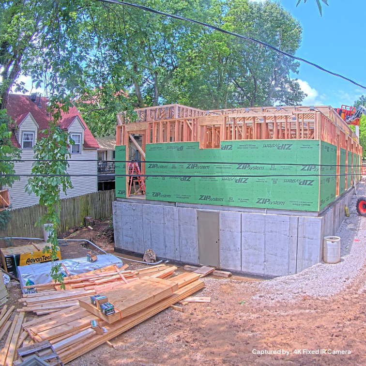 A construction site with building materials sitting out and a project in the framing stage. Captured by a TrueLook Camera. 