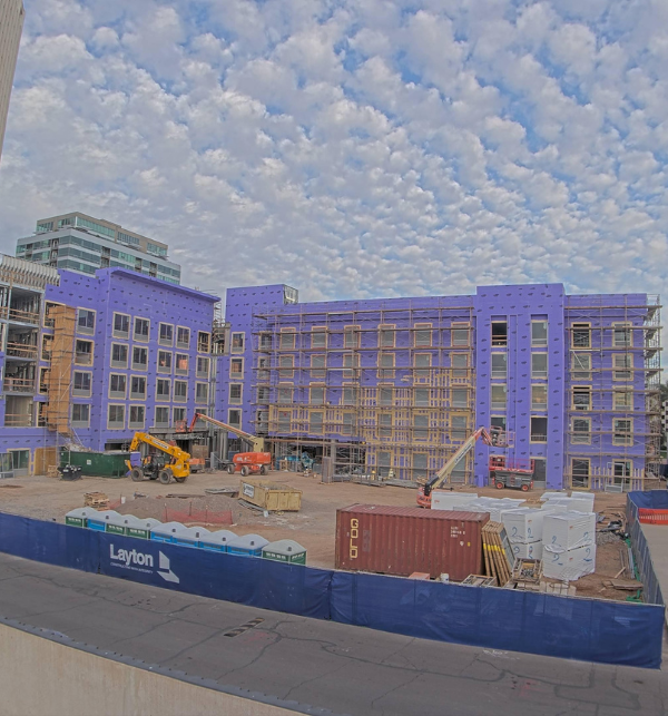 A hotel under construction with excavators and boom lifts on site. Captured by a TrueLook Construction Camera