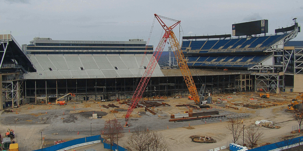 Two cranes in the air working on construction of the Penn State Beaver Stadium