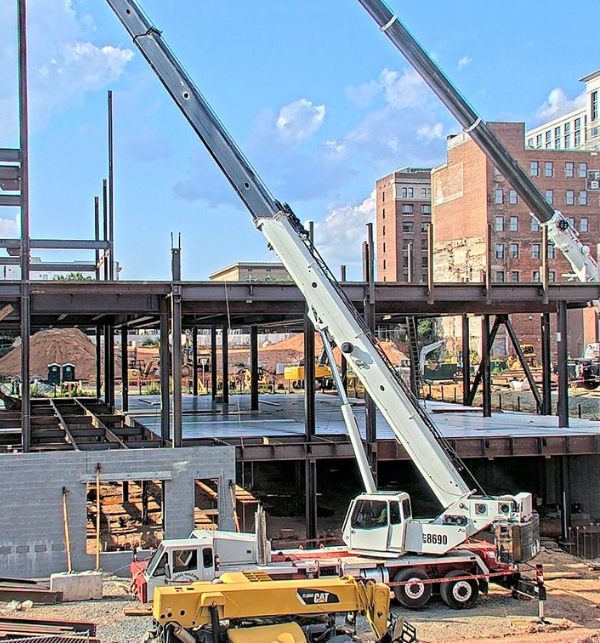 Active construction site with multiple boom lifts and steel being erected on the site of the Kaleideum in Winston-Salem