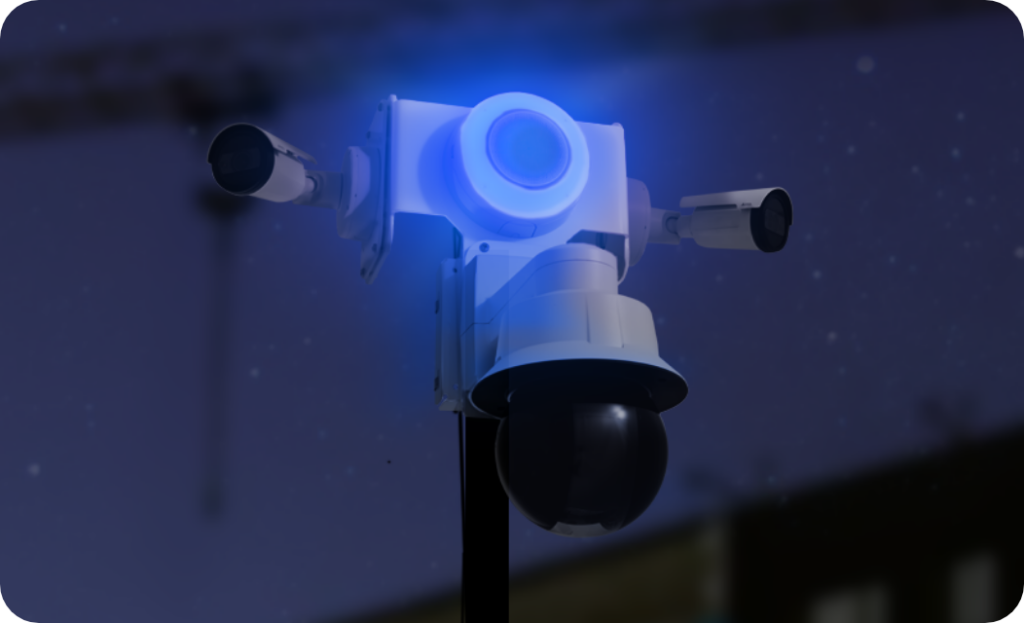 Construction site security camera with a ptz camera, two fixed cameras and a strobe and siren lit up during nighttime