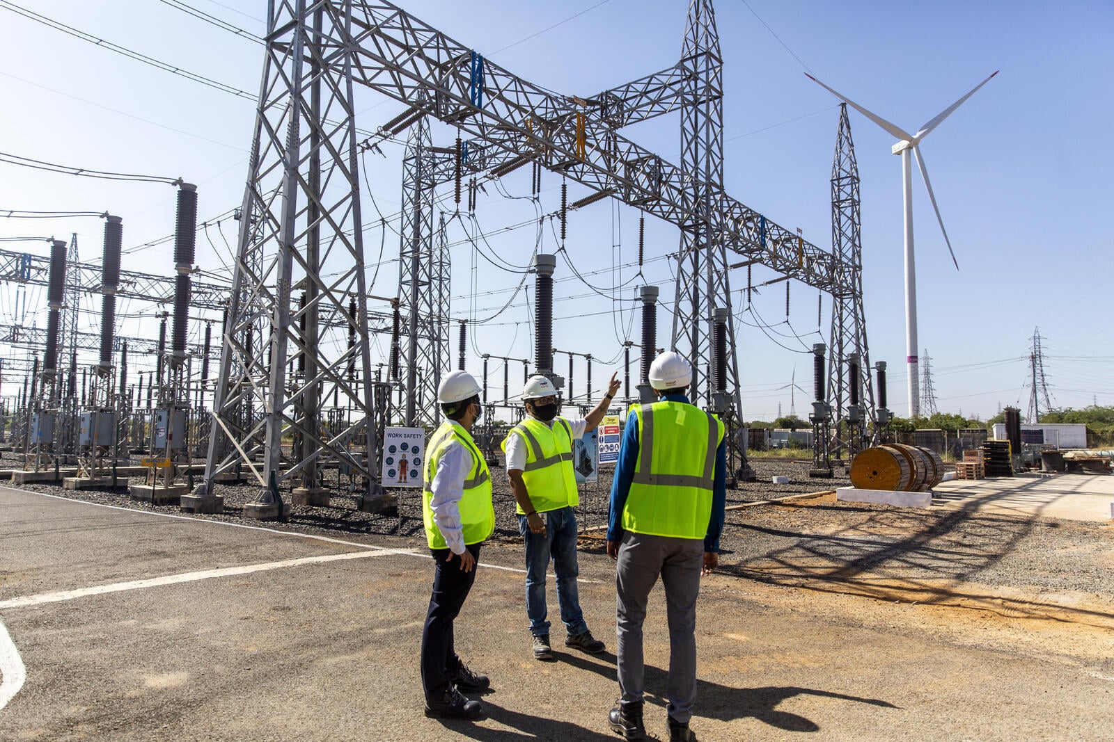 a team of construction workers talking about energy sector security at a substation