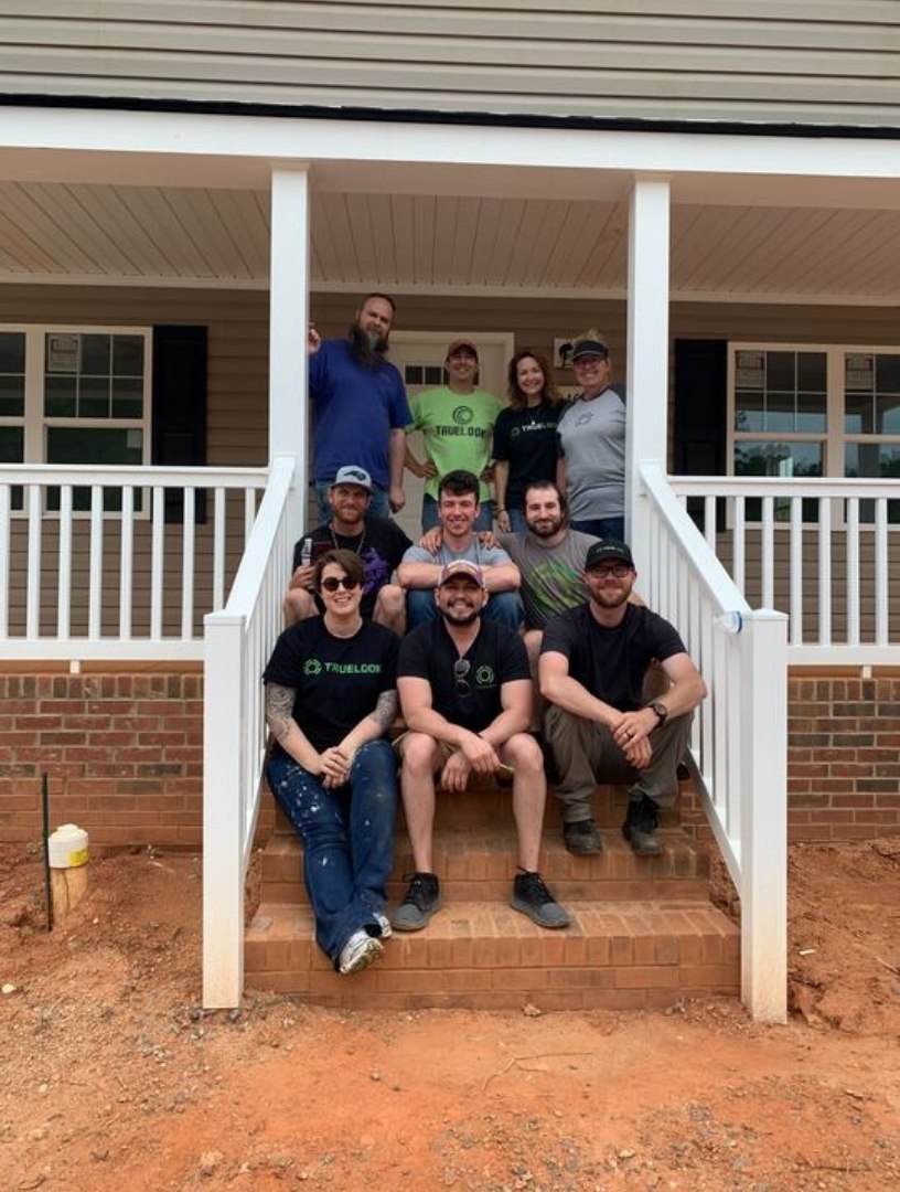 TrueLook volunteer team posing on the porch of a newly built home