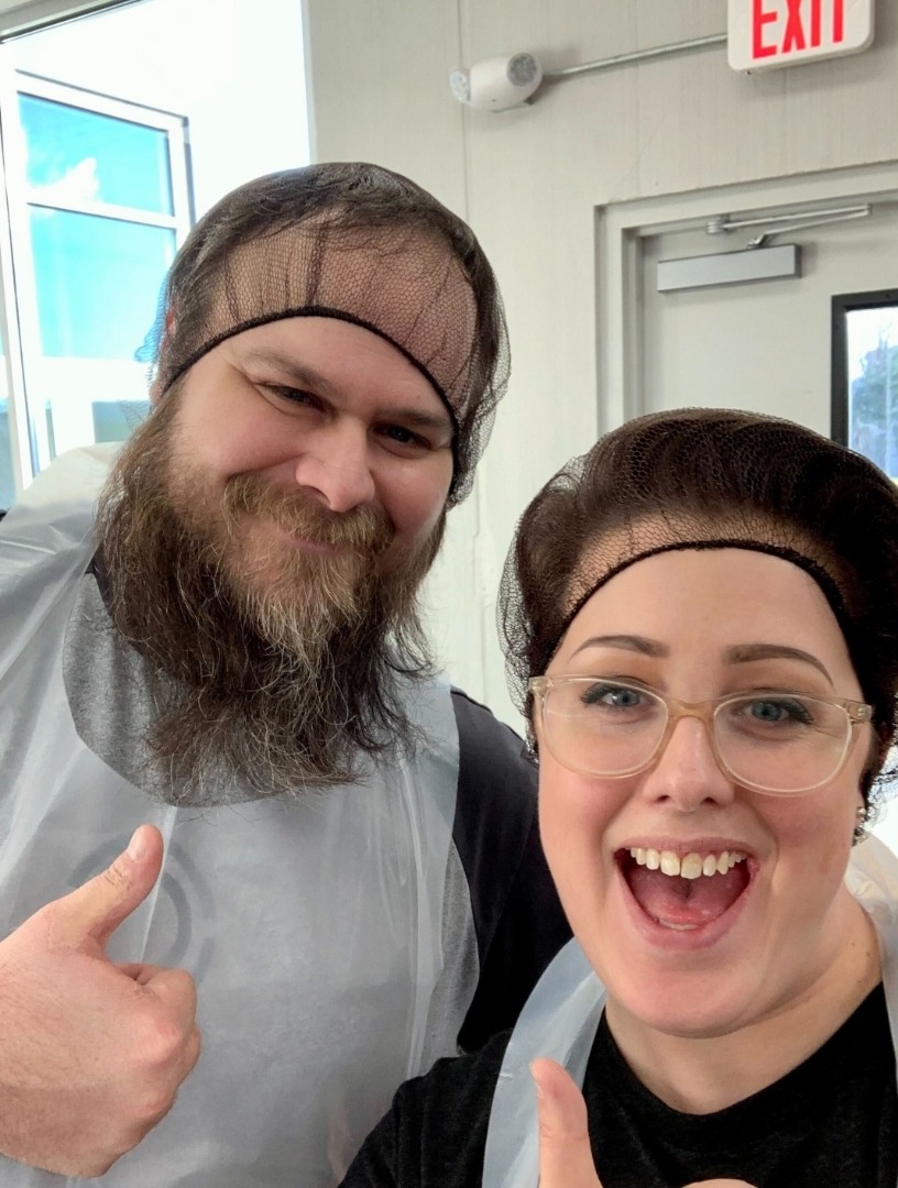 Two TrueLook volunteers in hairnets giving a thumbs-up at a food service event