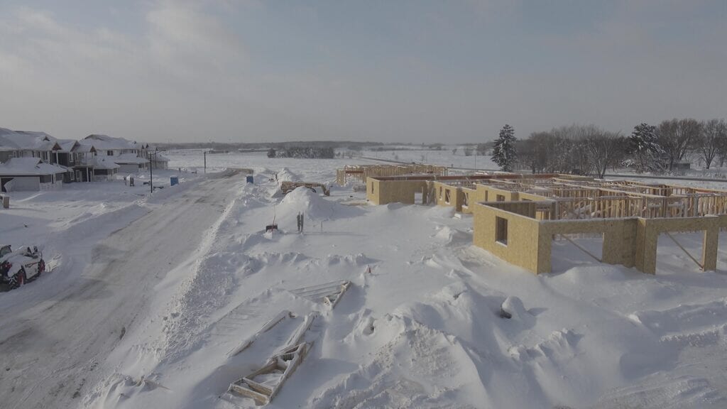 Multiple inches of snow piled up on a construction site where there is half of a townhome community being built