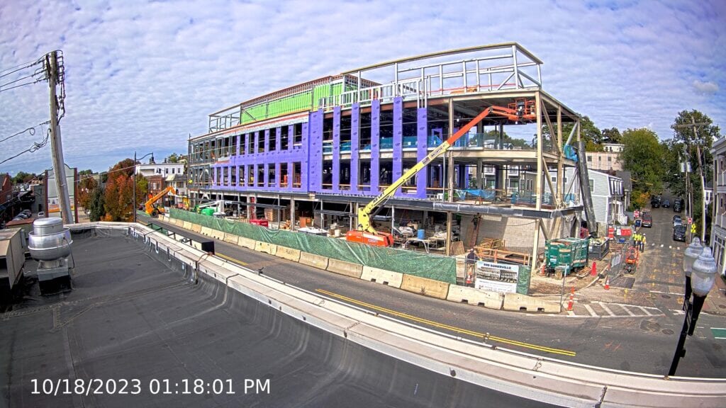 A timestamped image of a construction site in the middle of construction with some sheathing on the walls and steel beams. Taken by a construction camera on the building across the street.