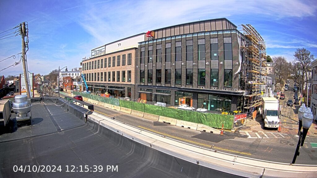 A timestamped image of an apartment building under construction with some scaffolding on the side. Taken by a construction camera on the building across the street.