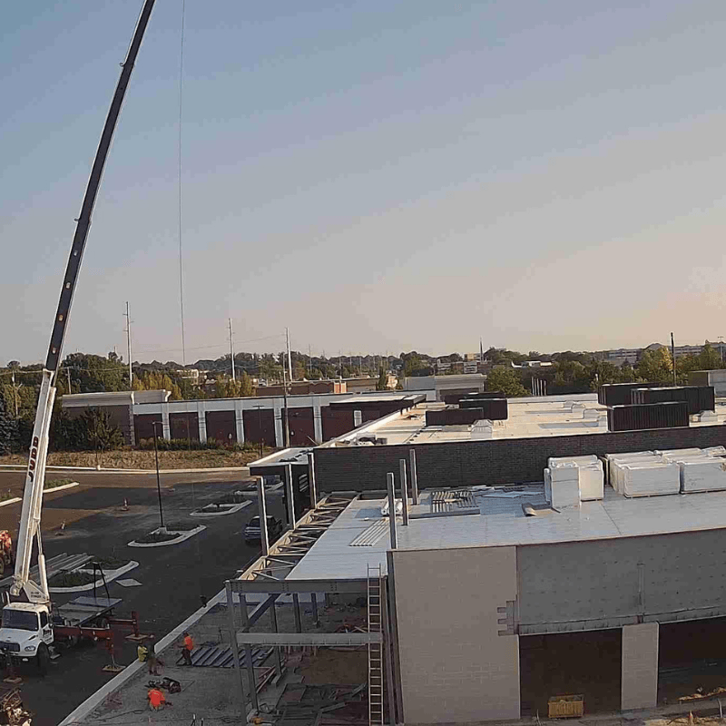 Camera view of a commercial building under construction with a crane