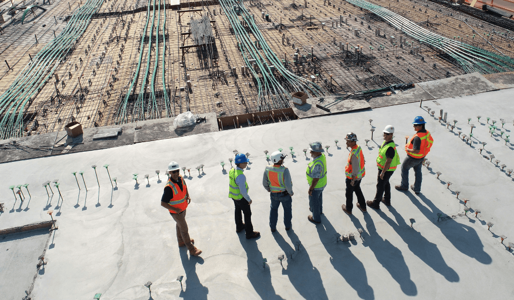 7 construction workers in PPE looking at a substation