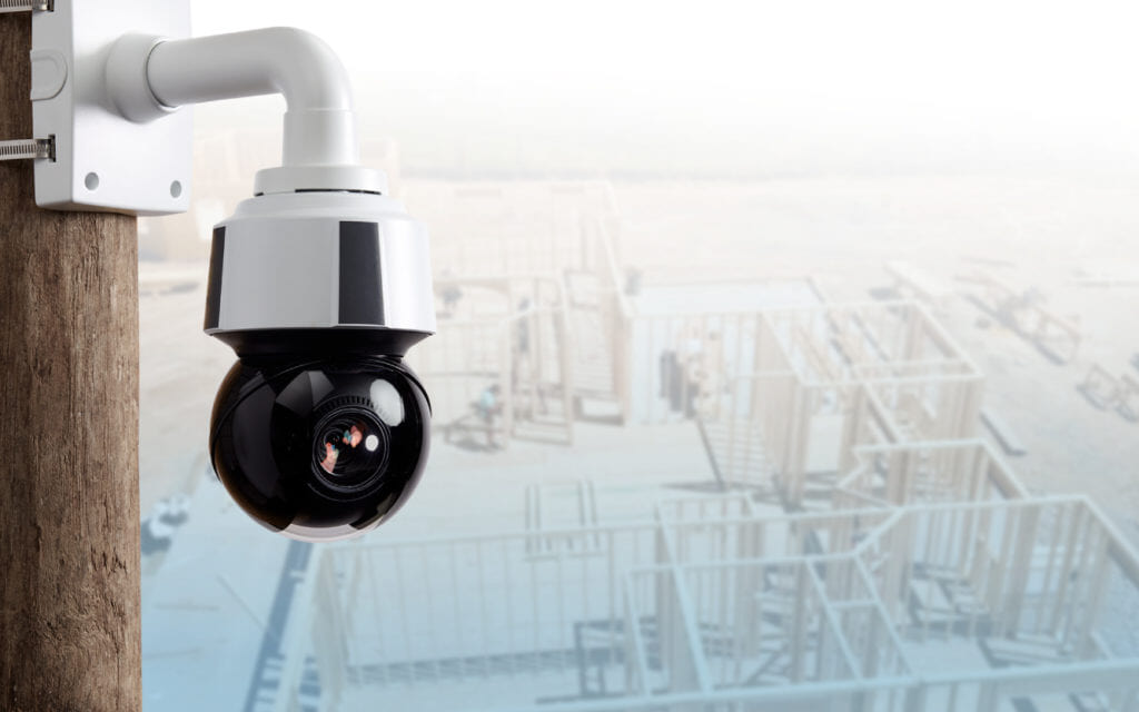 Pan-tilt-zoom camera on a pole over a faded building frame