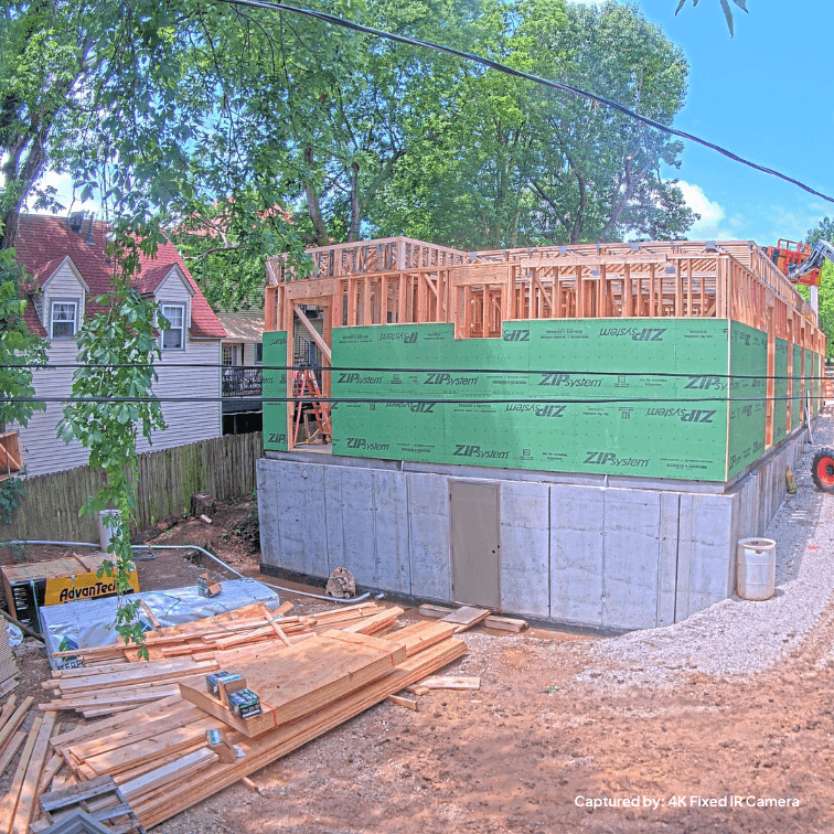 A construction site with building materials sitting out and a project in the framing stage. Captured by a TrueLook Camera.