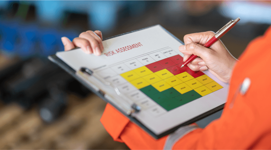 Hand filling out a risk assessment matrix on a clipboard