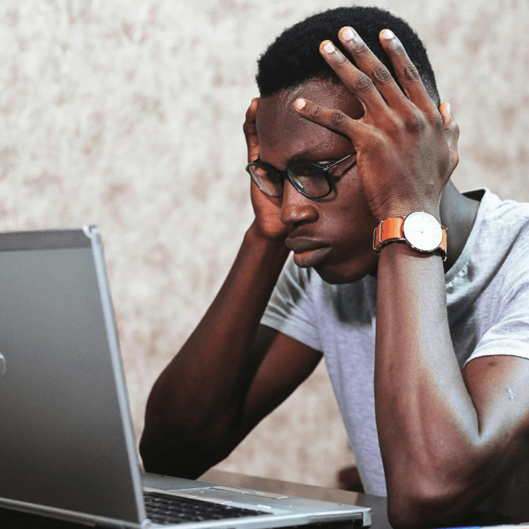 Stressed man with his head in his hands at a laptop