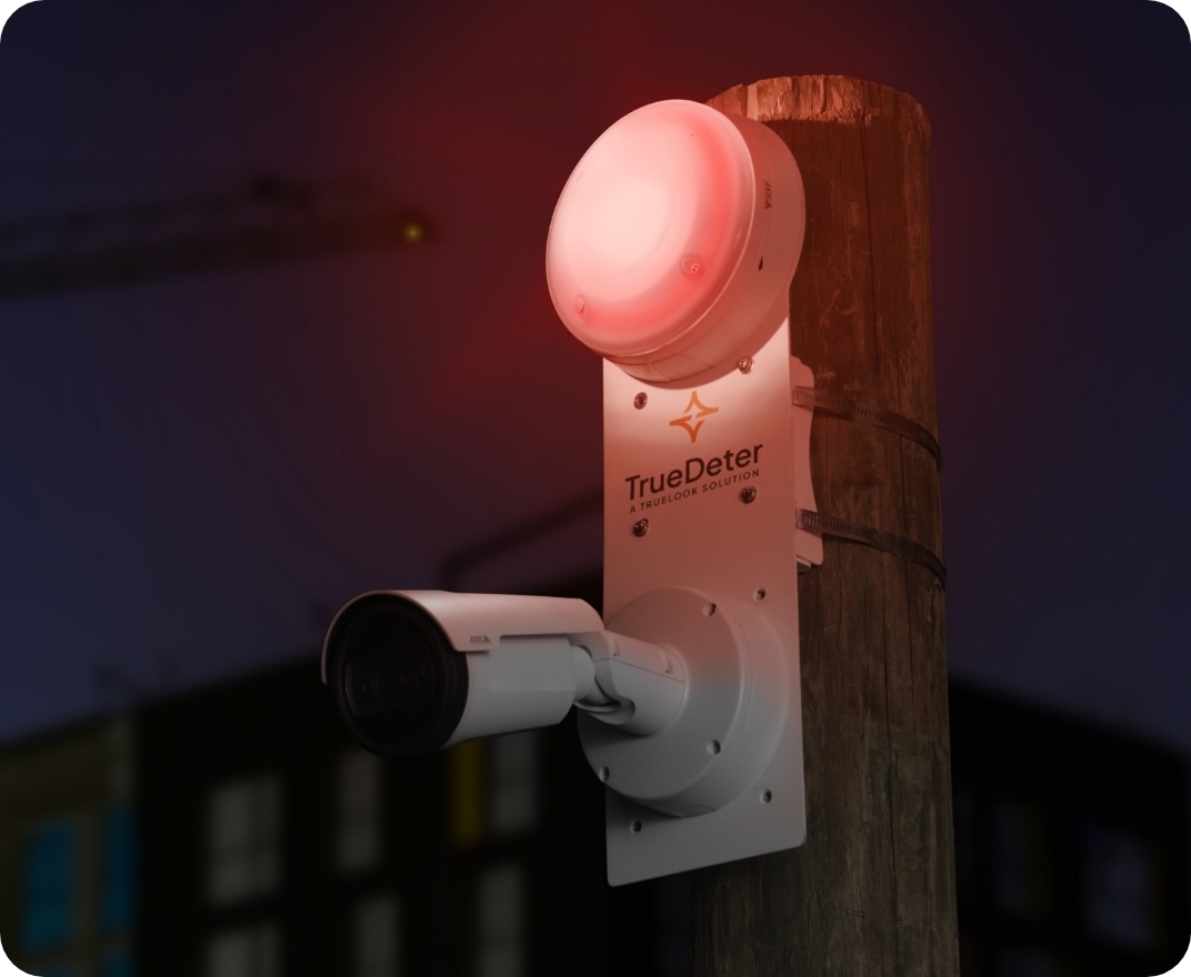 TrueDeter camera with red strobe light mounted on a wooden pole at night