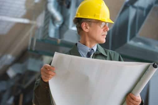 Engineer in a hard hat holding rolled plans