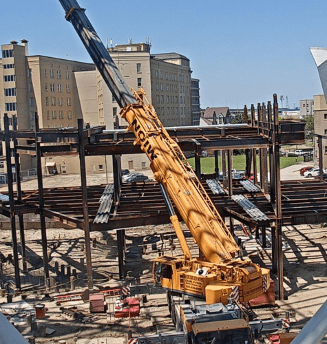 Crane setting steel beams on a building frame