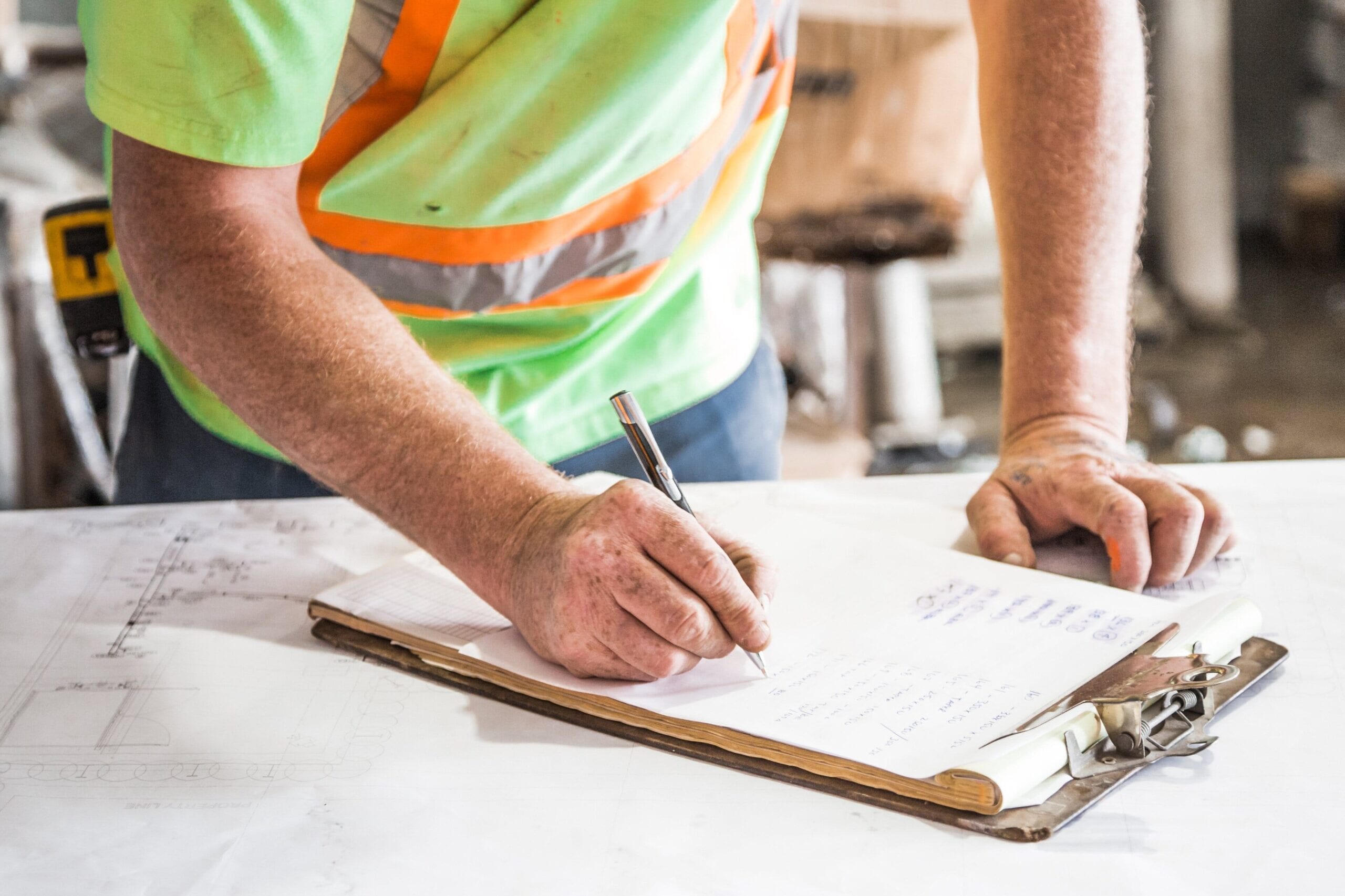 A construction worker writing things down with a pen on a clipboard