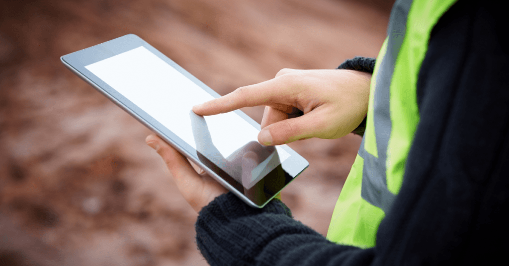 A construction worker in PPE using an iPad on the jobsite