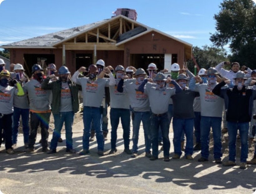 Group of volunteers in matching shirts in front of a house under construction