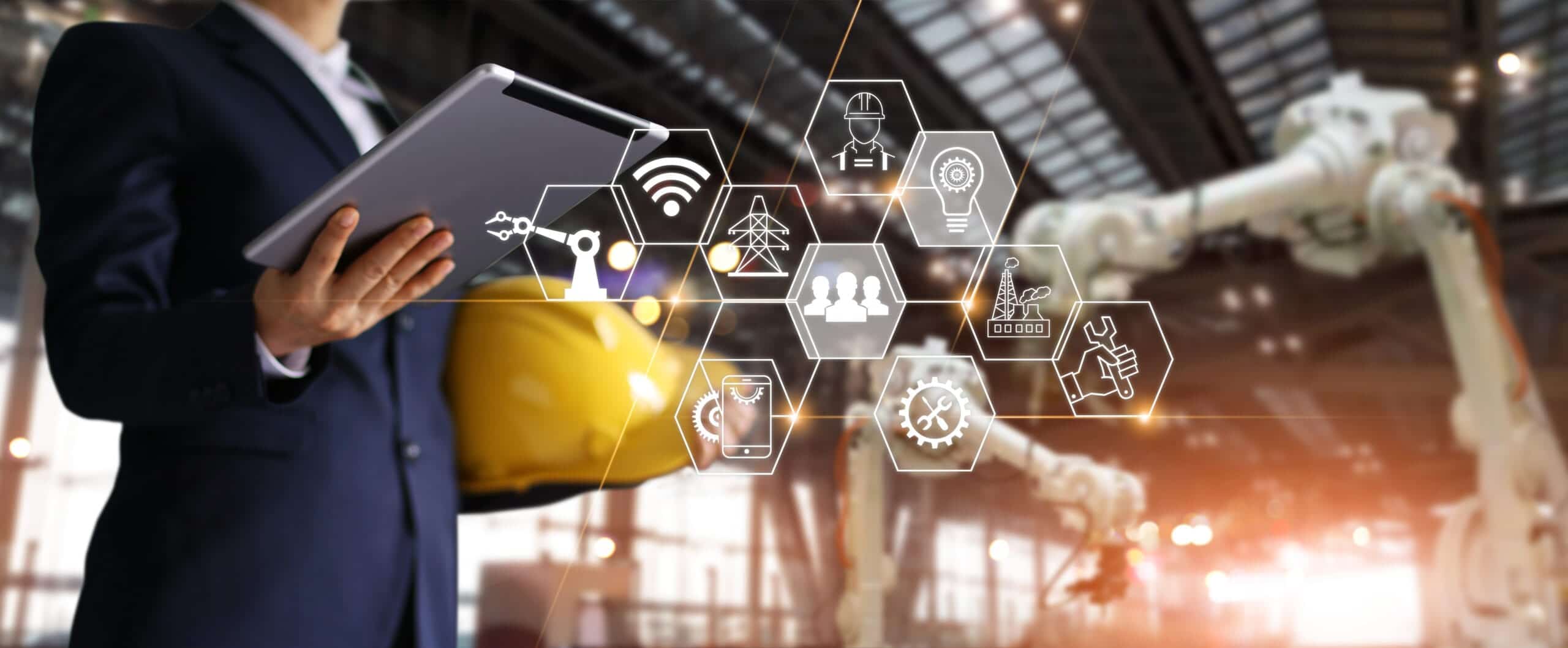 Businessman holding a tablet with technology icons and a robotic arm
