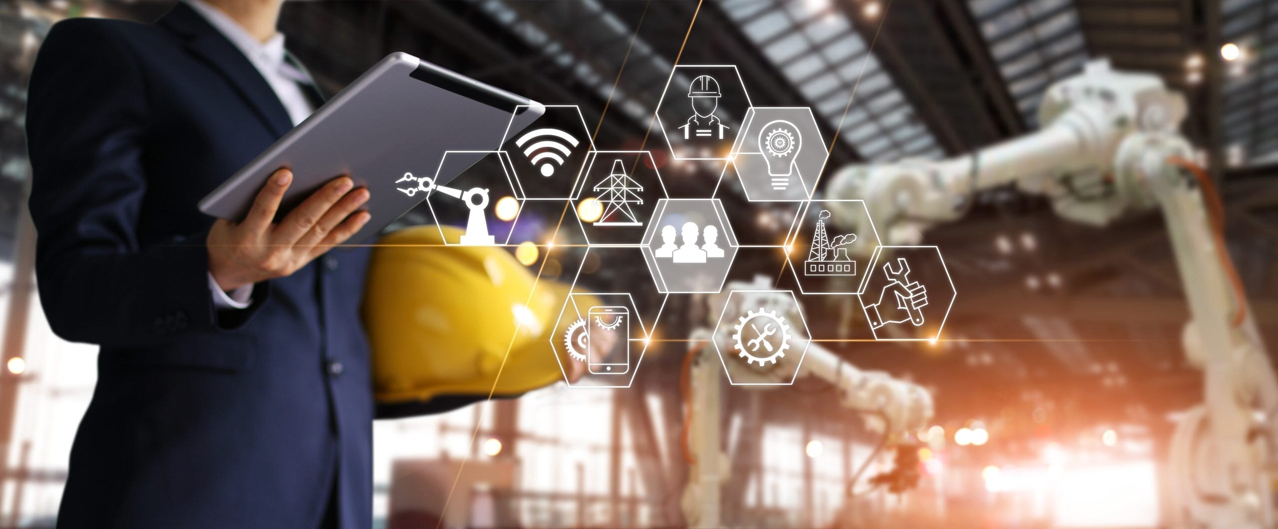 A construction worker in a suit holding a hard hat and an iPad with icons coming out of the iPad/tablet