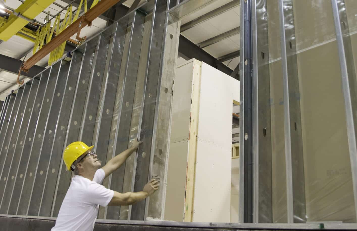 Worker in a hard hat inspecting a prefabricated wall panel