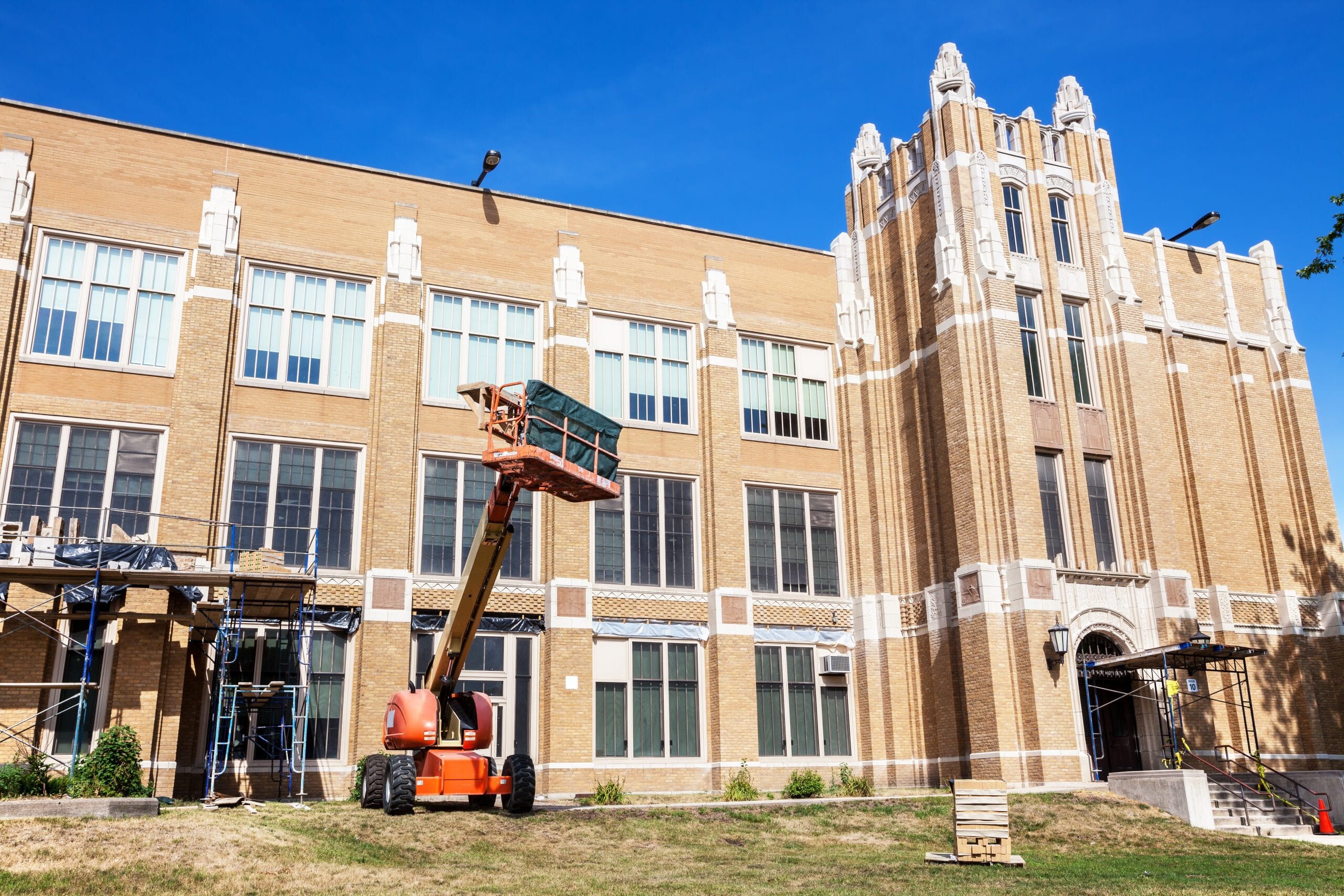 Aerial lift beside a historic school building under renovation
