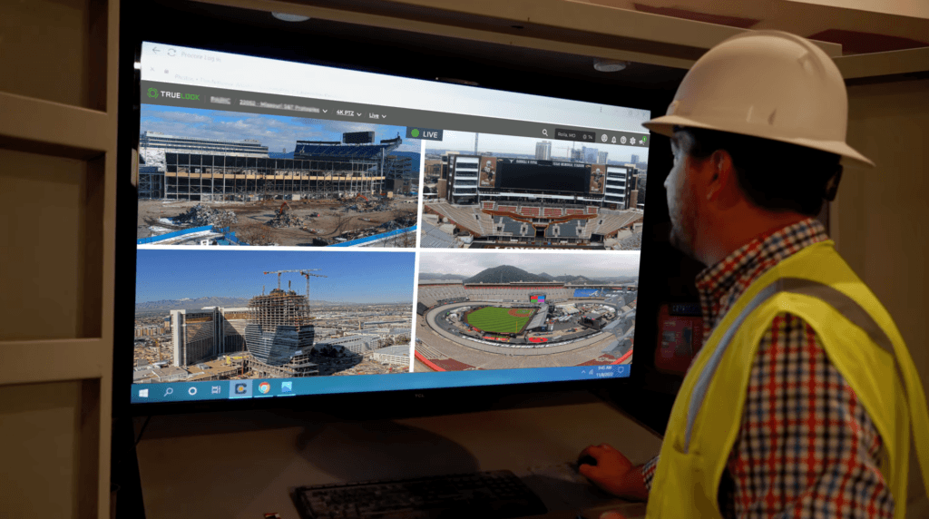 Man in a hard hat viewing four live camera feeds on a monitor