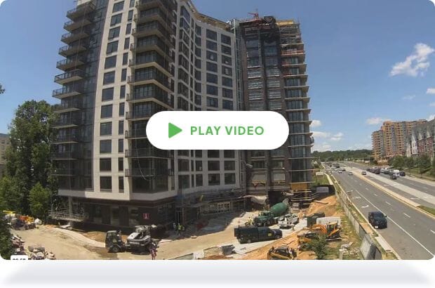 A play button on a time-lapse of a high-rise from a construction site camera
