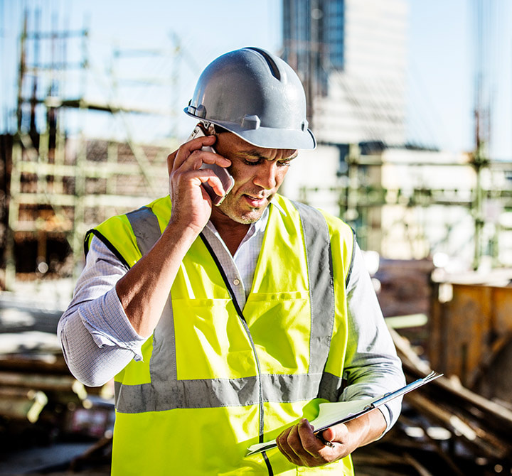 Superintendent on site talking on the phone and holding an iPad