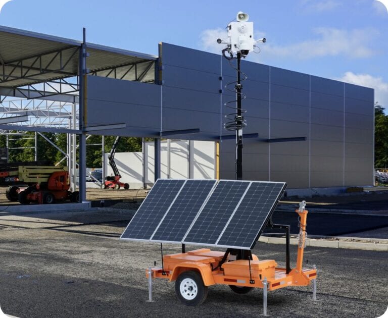 TrueShield solar-powered security trailer with mast cameras beside a building under construction