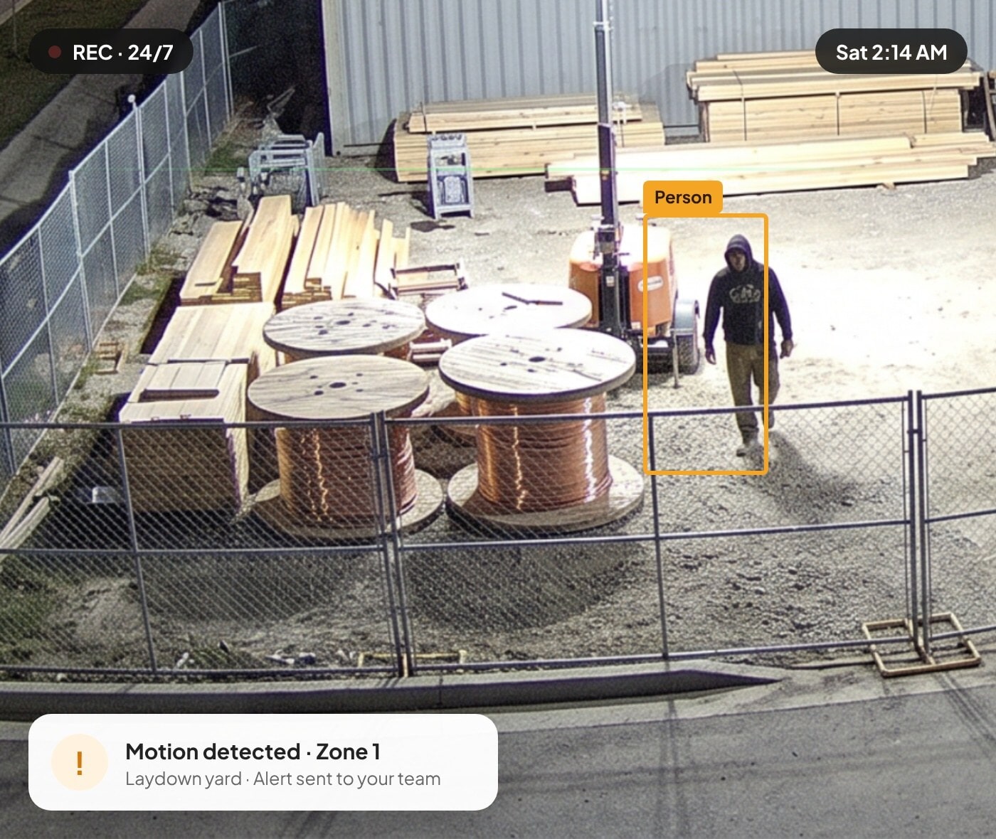 Night security camera detecting a person near copper wire spools with a motion alert
